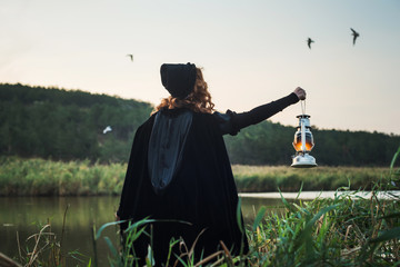 witch with light on a swamp. Witch practicing magic on a swamp. Halloween concept