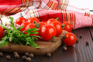 Cherry tomatoes, rucola, spices, garlic and salami on a cutting