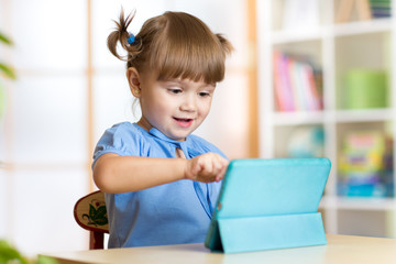 child girl playing with a digital tablet at home