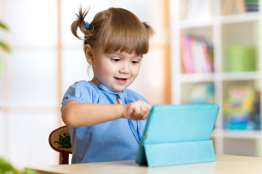child girl playing with a digital tablet at home