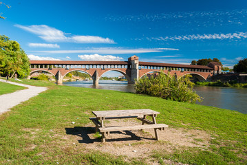 Table near the shore of river Ticino in Pavia; the "Ponte Coperto" in the background