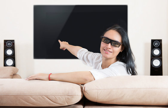 Woman in 3d glasses pointing at home cinema system