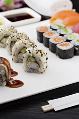 Sushi set with chopsticks and soy sauce over dark wooden background