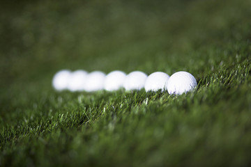 Repeatedly white golf balls on green grass