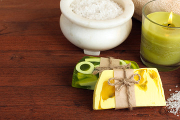 the soap and towel next to sea salt and candle on wooden background