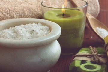 the soap and towel next to sea salt and candle on wooden background,filter