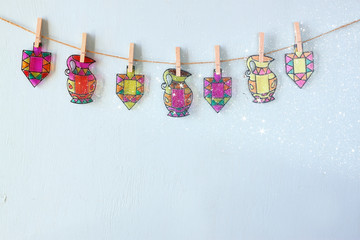 image of jewish holiday Hanukkah with Stained-glass colorful dreidels (spinning top) hanging on a rope over wooden background
