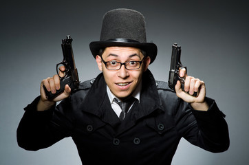 Criminal in black coat holding hadgun against gray