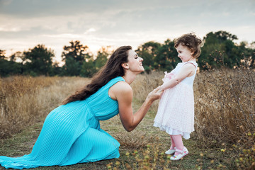 mother and daughter playing on autumn field together, loving family having fun outdoors