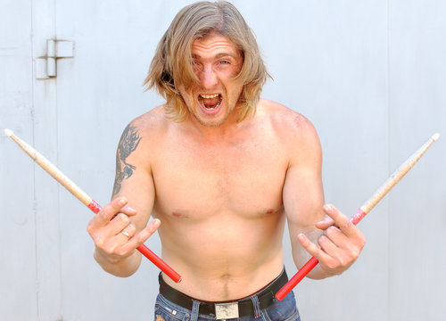 Angry drummer musician  having fun screams with drumstick
