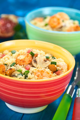 Couscous dish with shrimps, mushroom, almond, pomegranate seeds and green onion with forks on the side (Selective Focus, Focus on the tail of the shrimp on the top of the meal)