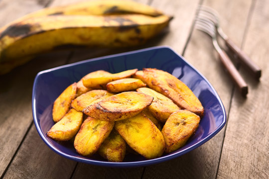 Fried slices of the ripe plantain, which is eaten as snack or accompaniment in South America (Selective Focus, Focus on the front of the upper plantain slice)
