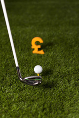 Targeting money with golf club and ball on green grass