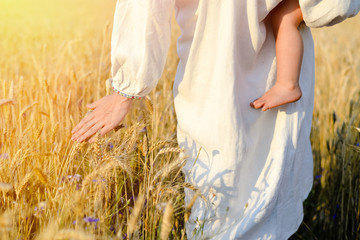 Picture of mother with child holding hand above wheat field on