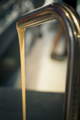 White chocolate flowing from a faucet metal
