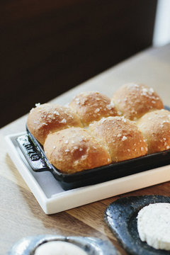 A tray of freshly baked bread rolls and cheese on a table top at a city restaurant. 