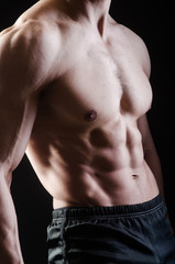 Muscular man posing in dark studio