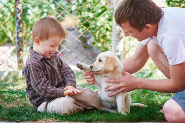 father and son playing with a puppy Labrador