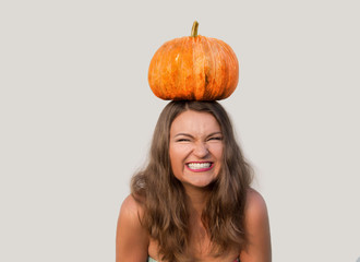 Giggling beautiful girl with halloween pumpkin on her head