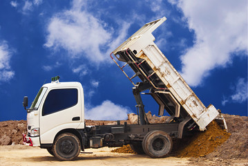  Dumper truck unloading soil or sand at construction site during road works at blue sky background