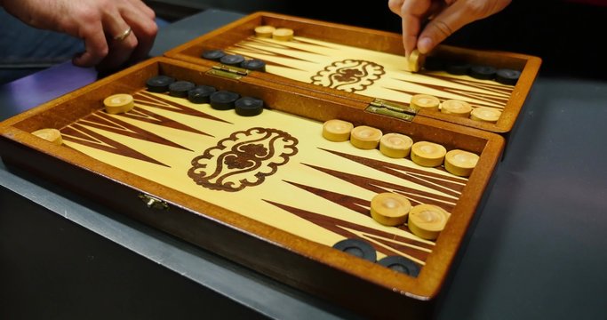Side shot of two people playing the backgammon