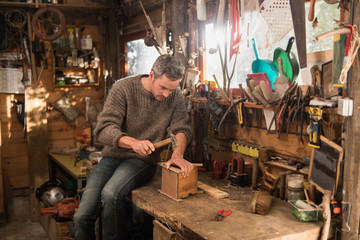 man with beard wearing wool sweater, working in his workshop