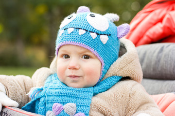 Happy baby in a funny hat on a walk. Walking outdoors in the fall. autumn leaves
