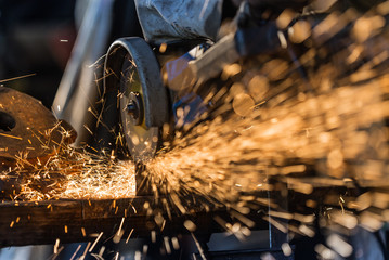 Worker cutting metal with grinder. - obrazy, fototapety, plakaty