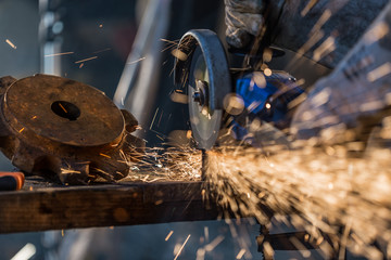 Worker cutting metal with grinder. - obrazy, fototapety, plakaty