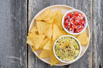 guacamole, tomato salsa and corn chips on a plate, top view 