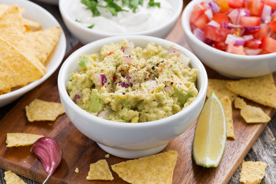 guacamole, tomato salsa and corn chips on table