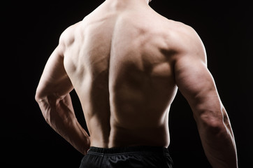 Fototapeta na wymiar Muscular man posing in dark studio