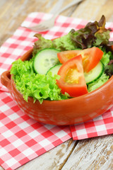 Green salad in clay bowl on checkered napkin
