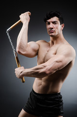 Muscular strong man with nunchucks 