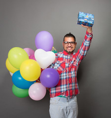 Handsome hipster man with baloons and a present in studio