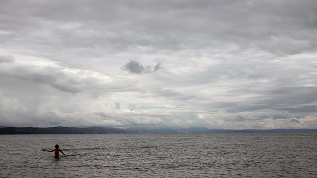 Kids swimming on a cludy day time lapse
