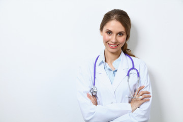 Friendly smiling young female doctor, standing near wall