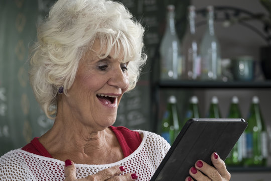 Senior Woman Using An Ipad/tablet In A Coffee Shop