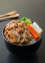 pork teriyaki with rice and vegetable on black bowl