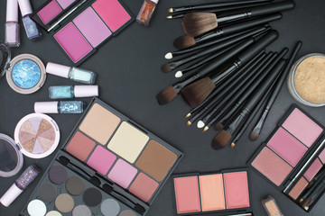 varsity size makeup brushes set with many tone of blushers,eyeshadows,highlighter,powder and nails paint on blackboard background