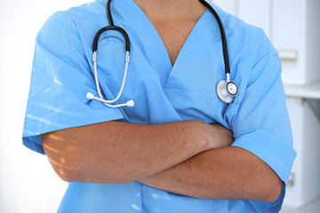 Portrait of unknown male surgeon doctor standing near the wall in hospital office, stethoscope