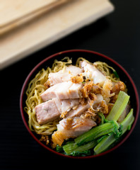 yellow noodle with crispy pork on black background