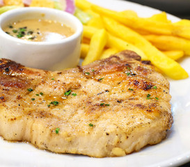 pork chop steak with salad and french fries on white dish