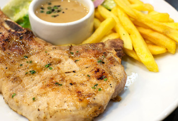 pork chop steak with salad and french fries on white dish