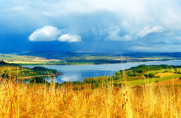 Beautiful landscape, yellow meadow and lake  in background.