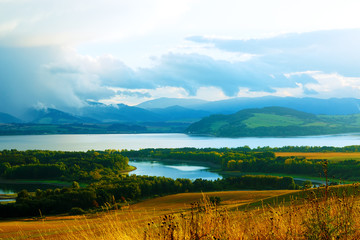 Beautiful landscape, yellow meadow and lake with mountains 