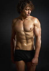 Naklejka premium Healthy muscular young man on black background.