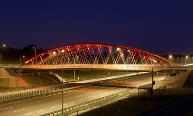 Fototapeta na wymiar Red steel bridge over brand new highway in the night.