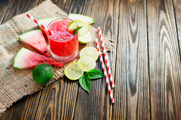Watermelon smoothie with mint and slices of lime on the wooden background