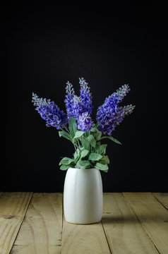 Lavender flowers in white vase on a black background